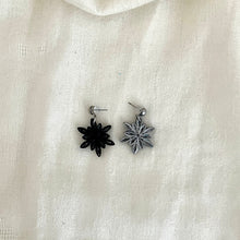 Load image into Gallery viewer, Paper quilled Snowflake earrings in black with silver edge color. One earring is showing the front side (silver color) and the other earring is showing the back side (black color).
